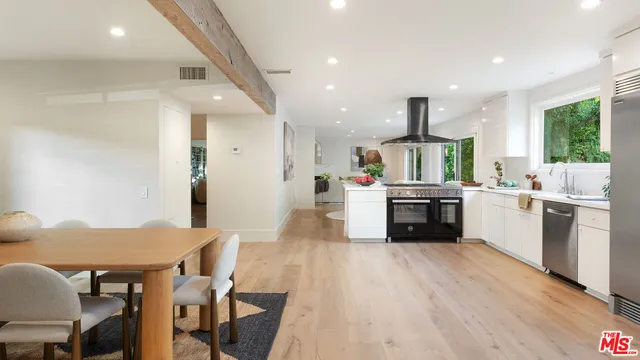 a kitchen with stainless steel appliances a sink a stove a refrigerator cabinets and wooden floor