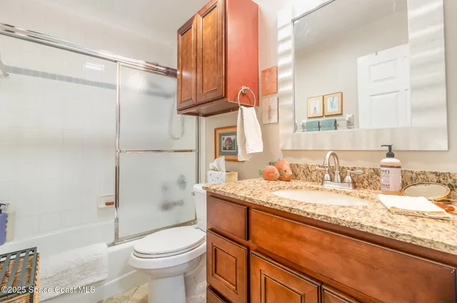 a bathroom with a granite countertop sink toilet mirror vanity and bathtub