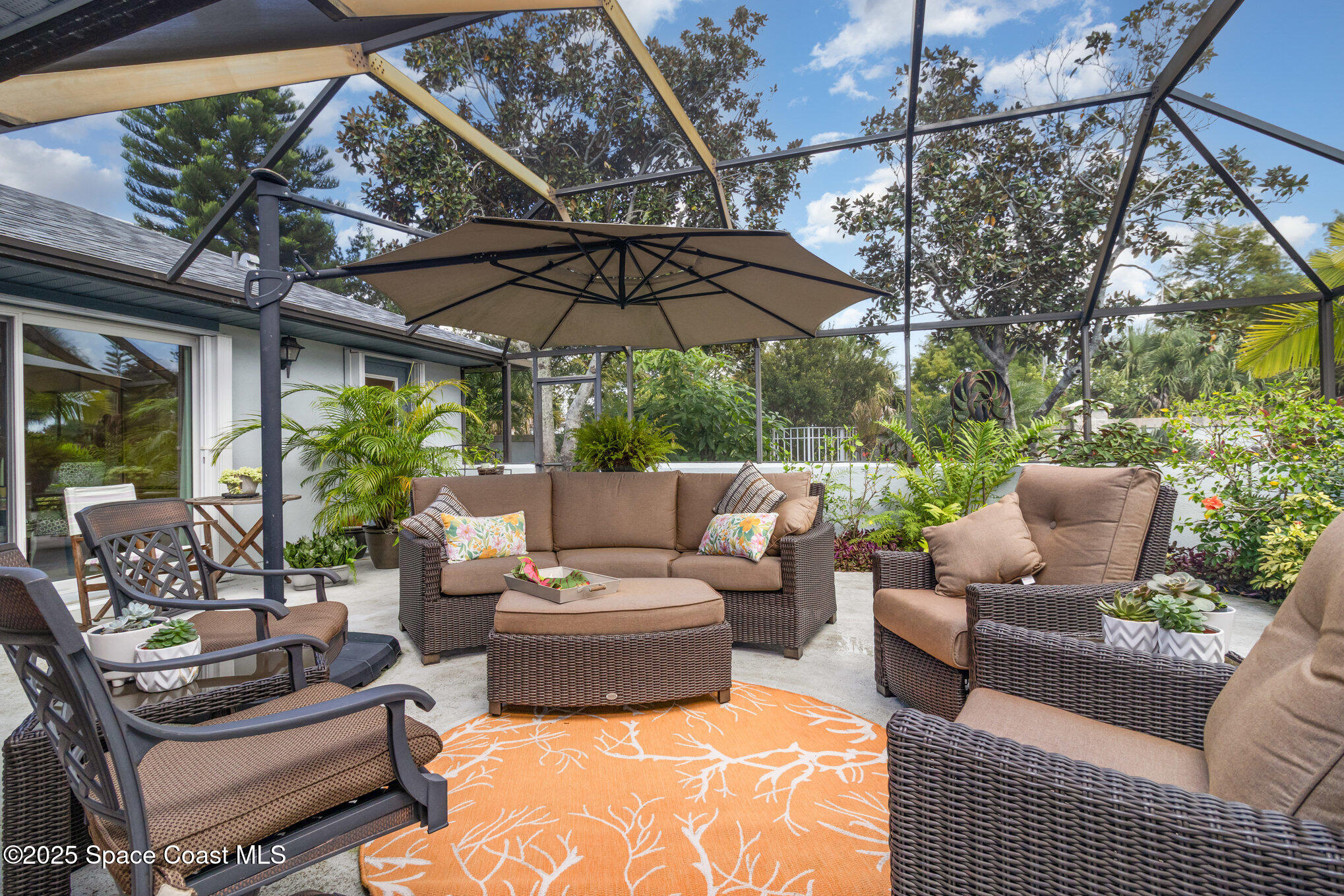 1484 Independence Avenue Melbourne, FL 32940 - Photo 16 of 30 a view of a patio with couches table and chairs under an umbrella with a small yard
