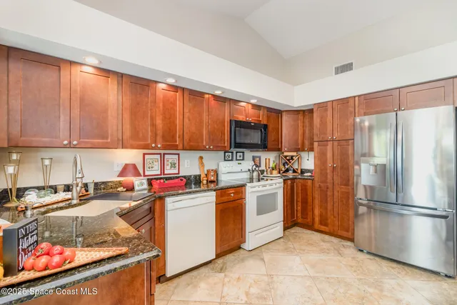 a kitchen with stainless steel appliances granite countertop a stove top oven a sink dishwasher and a refrigerator