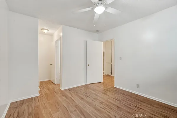 a view of a room with wooden floor and a ceiling fan