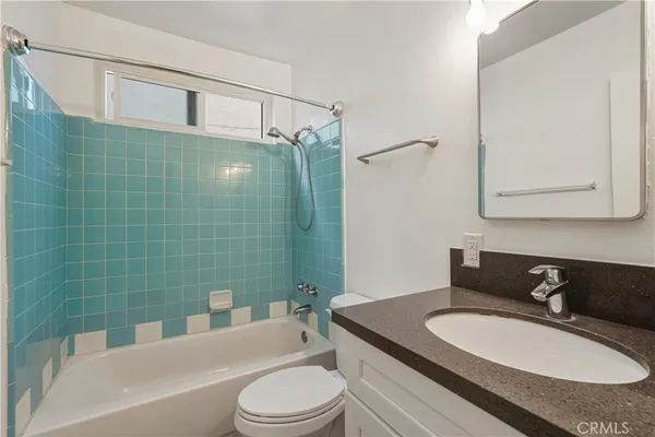 a bathroom with a granite countertop sink toilet a mirror and bathtub