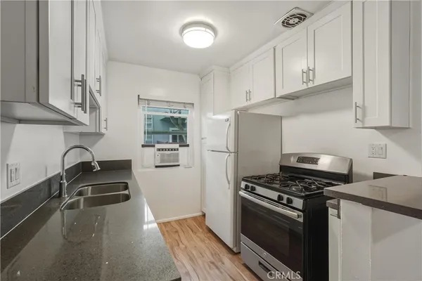 a kitchen with granite countertop a sink stove and refrigerator