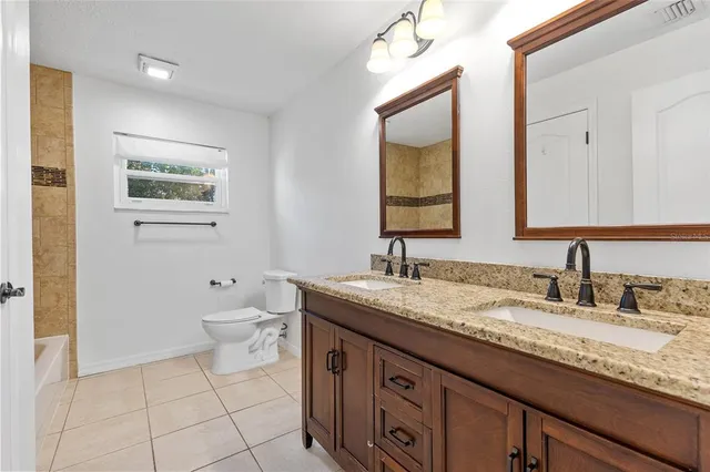 a bathroom with a granite countertop sink mirror and toilet