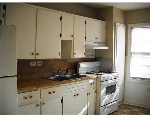 a kitchen with granite countertop a stove a sink and white cabinets