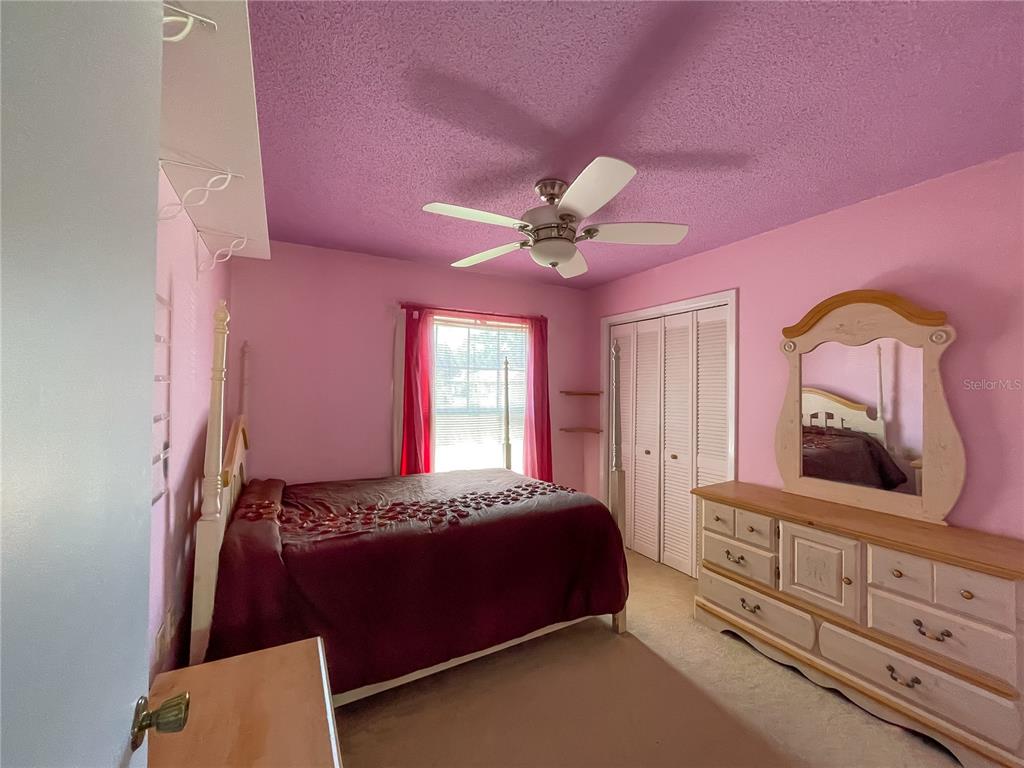 6336 Wooden Street New Port Richey, FL 34653 - Photo 8 of 13 a bedroom with a bed a chandelier and dresser
