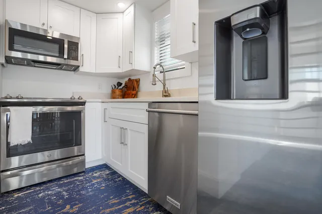 a view of a white house with a yard and potted plants