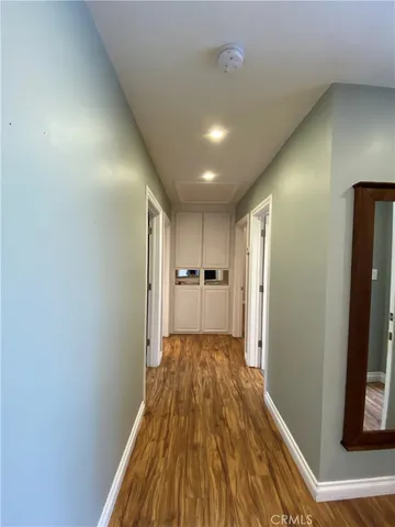 a view of a hallway with wooden floor and a refrigerator