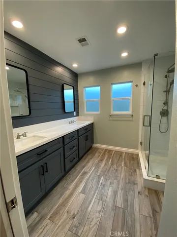 a spacious bathroom with a double vanity sink a mirror and shower