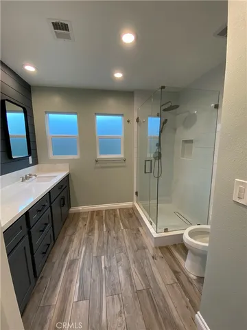 a bathroom with a sink a toilet a mirror and shower