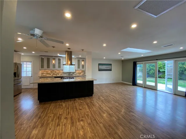 a large room with wooden floor and entrance to kitchen
