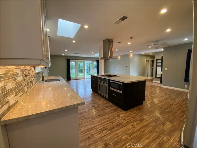 a large kitchen with stainless steel appliances a large counter top a stove and a refrigerator