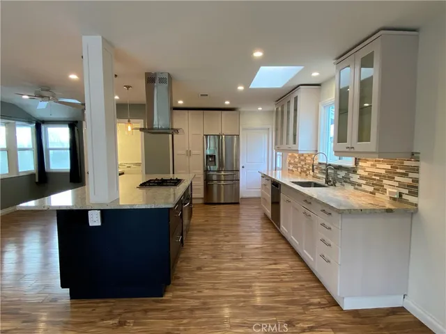 a large kitchen with stainless steel appliances a large counter top a sink and a refrigerator