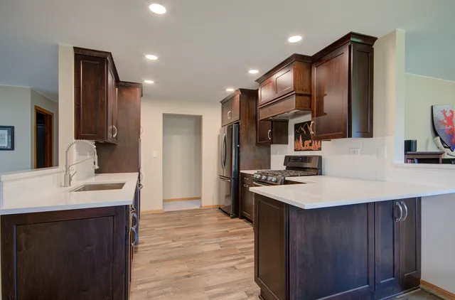 a kitchen with stainless steel appliances kitchen island granite countertop a sink refrigerator and cabinets