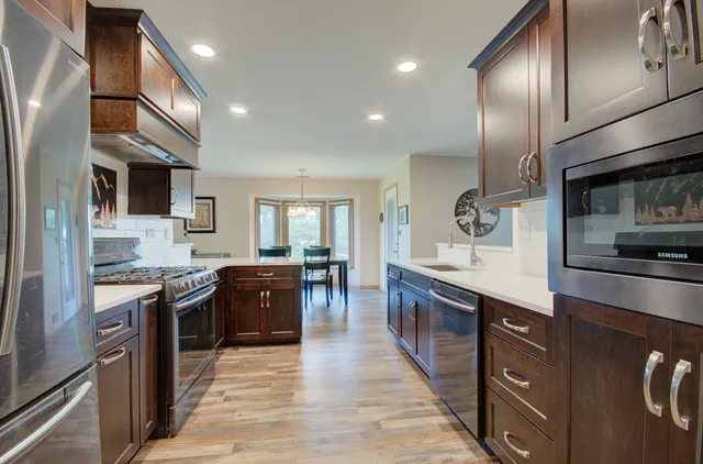 a kitchen with stainless steel appliances granite countertop wooden cabinets a sink dishwasher a stove and a refrigerator