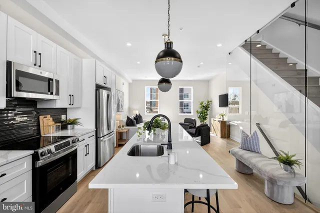 a kitchen with stainless steel appliances kitchen island granite countertop a refrigerator a stove a sink dishwasher and a dining table with wooden floor