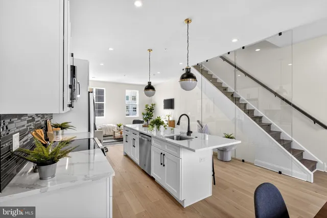 a kitchen with stainless steel appliances kitchen island hardwood floor sink and living room view