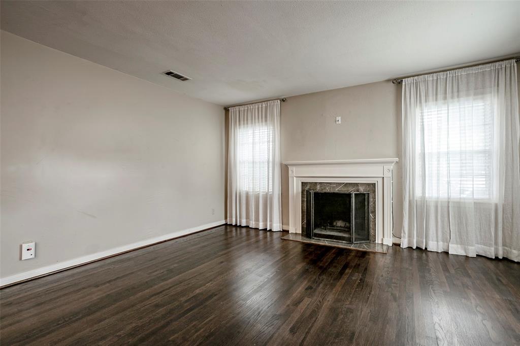 7410 Caillet Street Dallas, TX 75209 - Photo 4 of 25 an empty room with wooden floor fireplace and windows