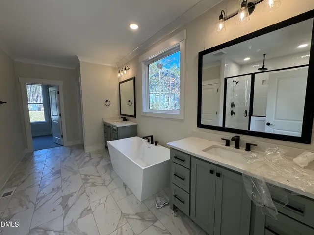 a bathroom with a sink double vanity granite tub shower and mirror