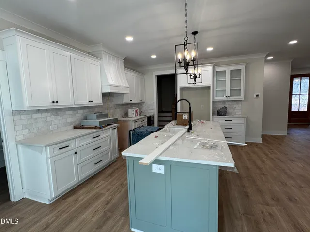 a kitchen with kitchen island granite countertop a sink cabinets and wooden floor