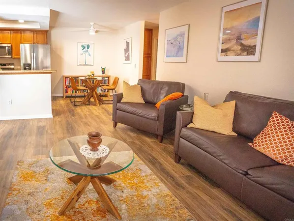 a living room with furniture and a dining table with wooden floor