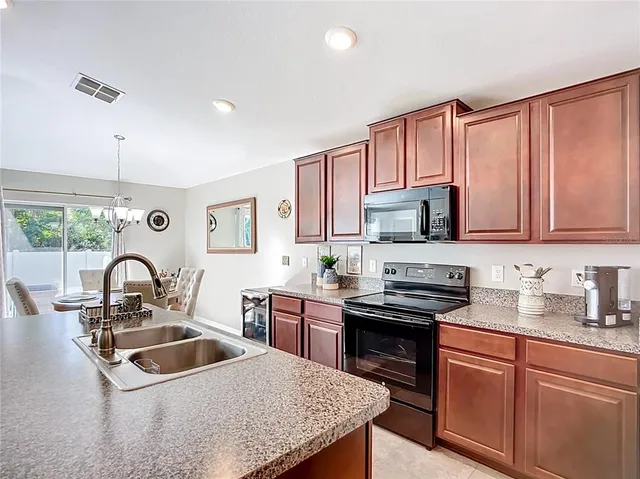 a kitchen with stainless steel appliances granite countertop a refrigerator oven a sink a stove a dining table and chairs