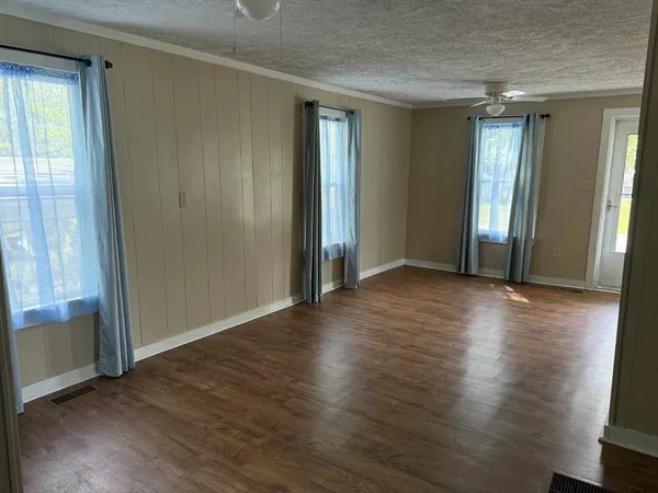 an empty room with wooden floor and windows