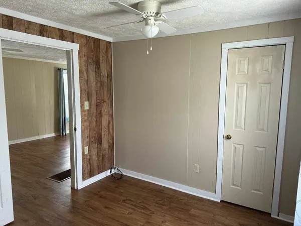 an empty room with wooden floor fan and windows