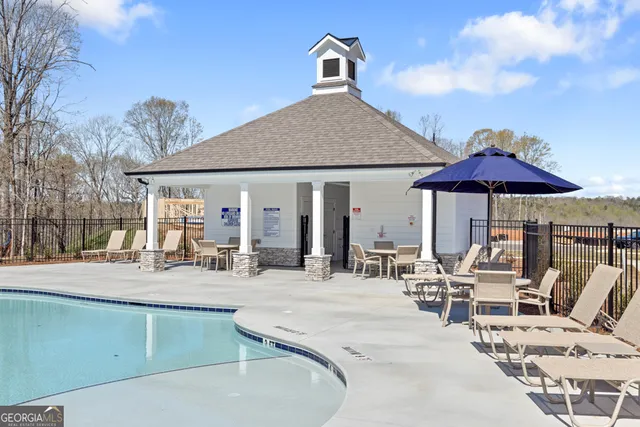 a swimming pool with outdoor seating and covered with trees