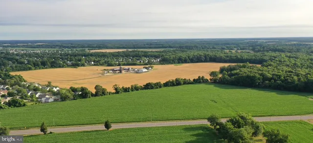 an aerial view of a houses with outdoor space and trees all around