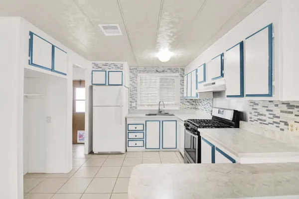 a kitchen with white cabinets and refrigerator