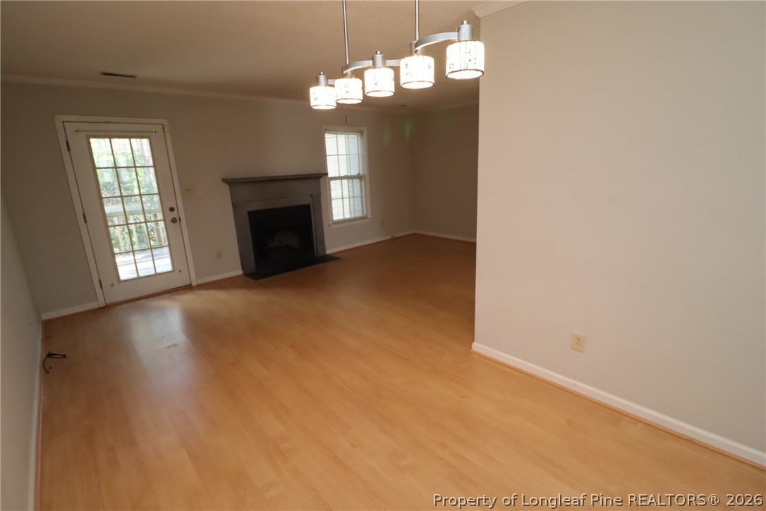 7424 Penny Hill Lane Raleigh, NC 27615 - Photo 10 of 30 an empty room with windows fireplace and chandelier