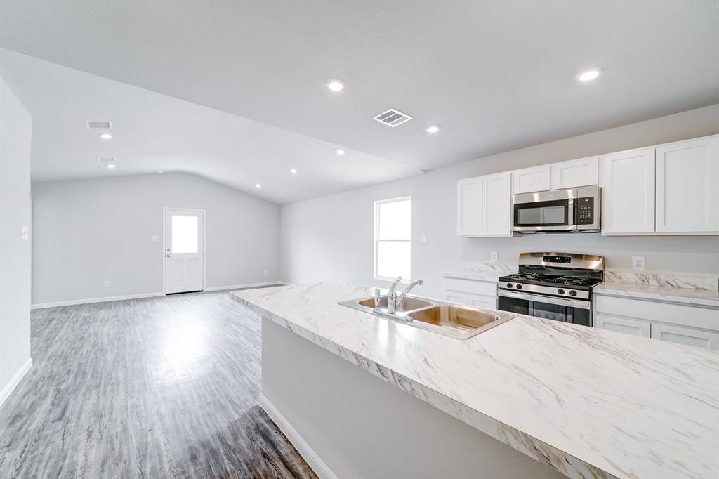 309 Victory Drive Mabank, TX 75147 - Photo 28 of 37 a kitchen with stainless steel appliances granite countertop a sink dishwasher stove and microwave with wooden floor