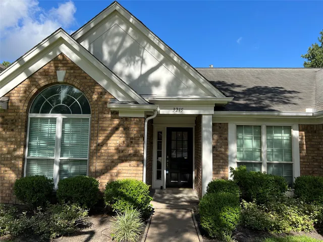 a view of a brick house with a large windows and plants
