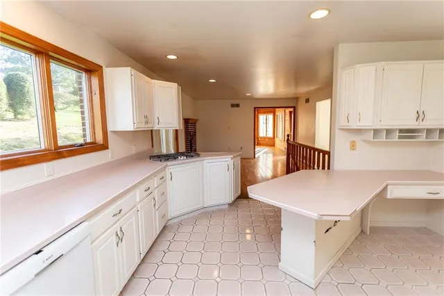 a kitchen that has a lot of white cabinets and wooden floor