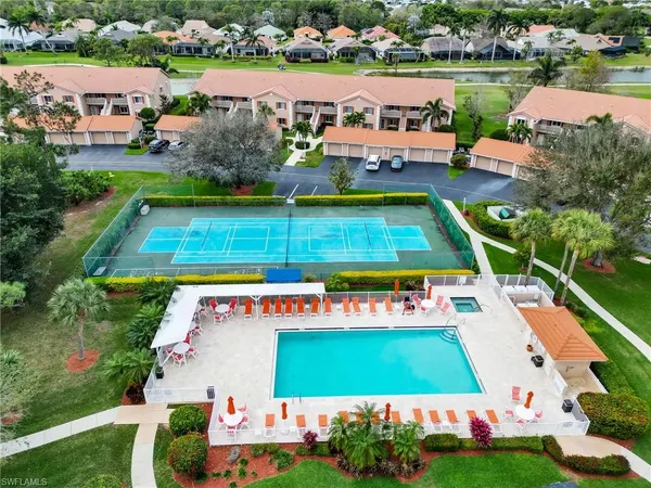 an aerial view of a tennis ground and a cars park side of the road