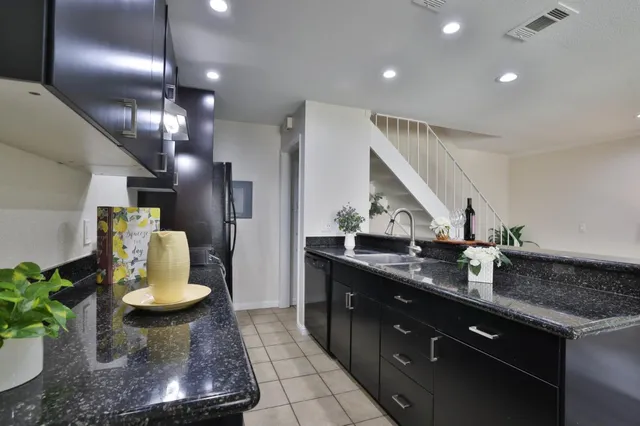 a kitchen with kitchen island granite countertop a sink stainless steel appliances and living room view