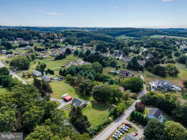 an aerial view of residential houses with outdoor space and trees