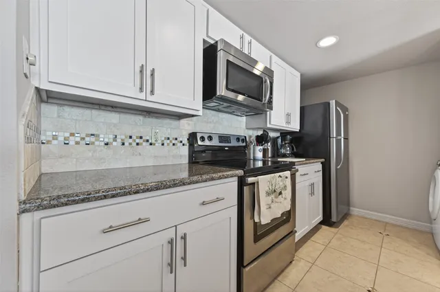 a kitchen with granite countertop a sink a counter space and cabinets