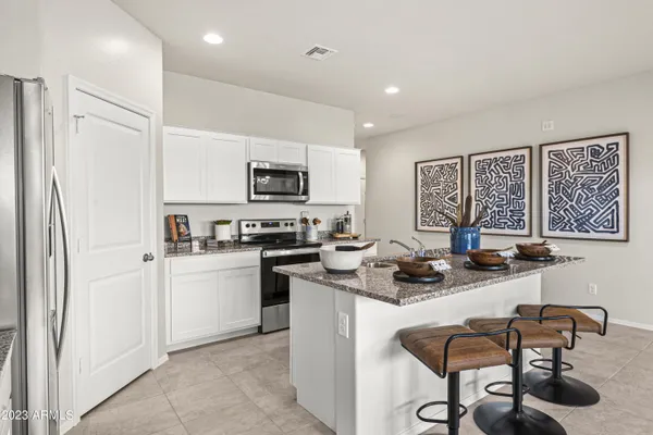a kitchen with stainless steel appliances granite countertop a stove top oven a sink a dining table and chairs