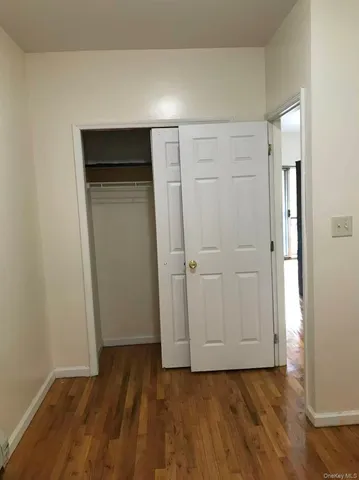 a view of an empty room with closet and wooden floor