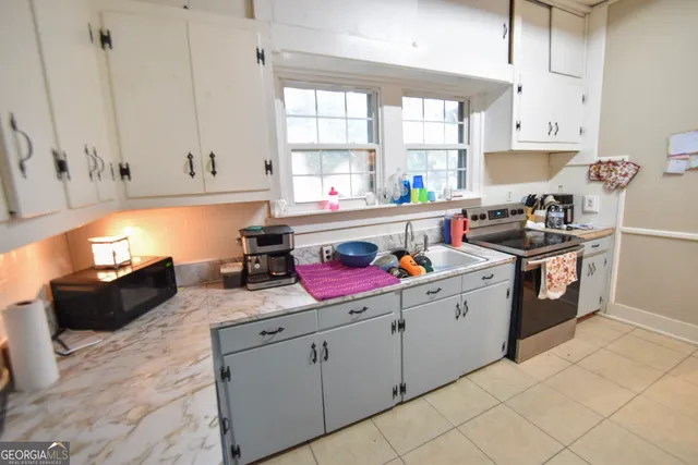 a kitchen with a sink dishwasher stove and white cabinets