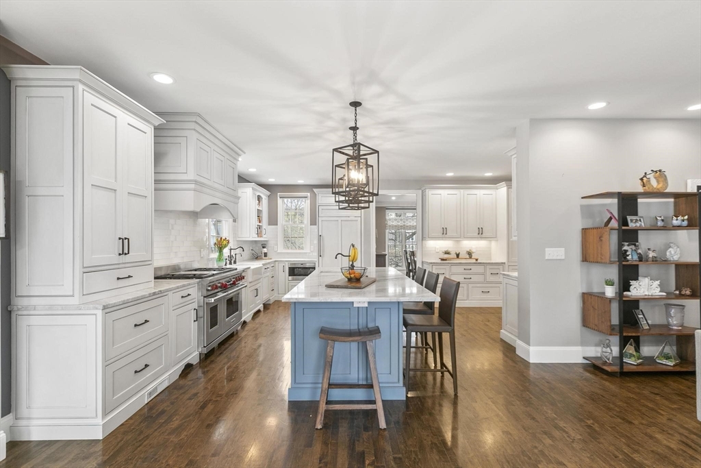 27 Sherman Street Lexington, MA 02420 - Photo 7 of 30 a kitchen with stainless steel appliances kitchen island granite countertop a stove a sink dishwasher and white cabinets with wooden floor