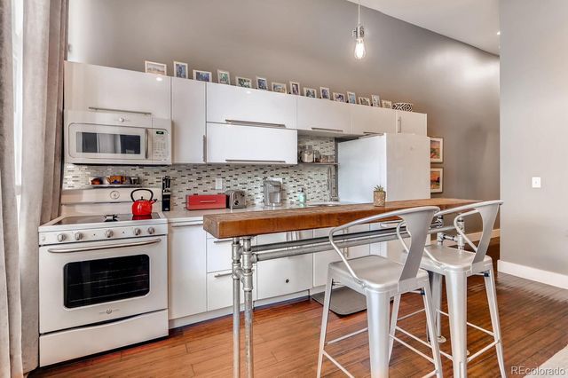 a kitchen with a stove and white cabinets with wooden floor