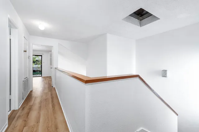 a view of a hallway with wooden floor and staircase