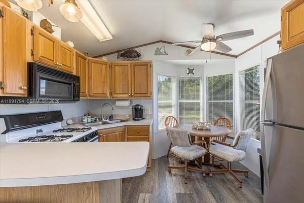 a living room with stainless steel appliances furniture a flat screen tv and a window