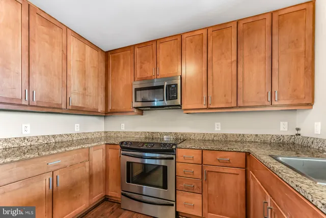 a kitchen with granite countertop stainless steel appliances sink microwave and cabinets