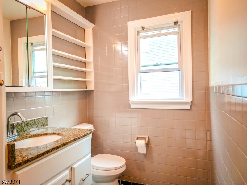 104 Eastern Way, Unit 2 Rutherford, NJ 07070 - Photo 12 of 18 a bathroom with a granite countertop toilet a sink and a window