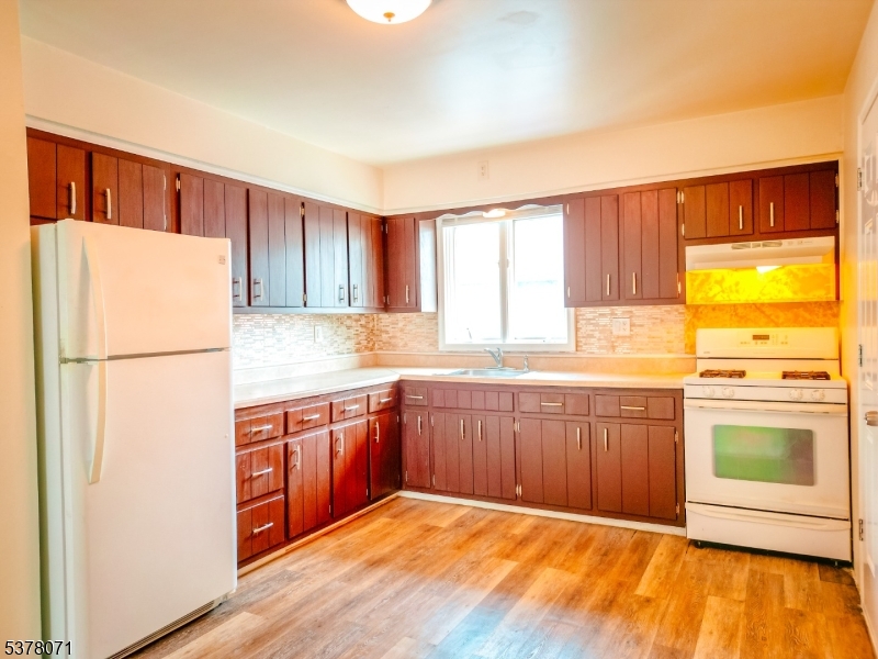 104 Eastern Way, Unit 2 Rutherford, NJ 07070 - Photo 18 of 18 a kitchen with stainless steel appliances granite countertop a refrigerator a sink dishwasher and wooden cabinets with wooden floor