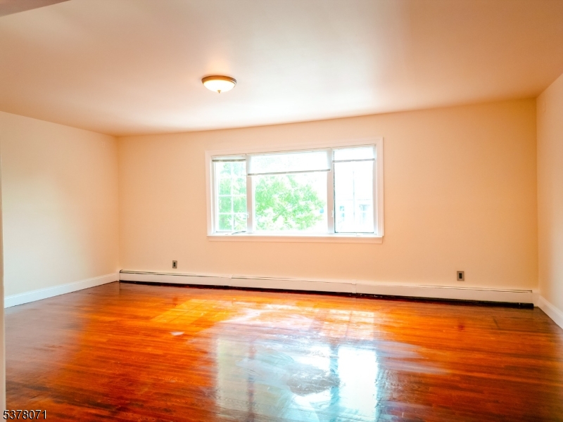 104 Eastern Way, Unit 2 Rutherford, NJ 07070 - Photo 3 of 18 a view of an empty room with wooden floor and a window